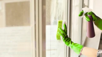 uma pessoa usando luvas verde, esponja e produto correto para limpar vidros