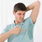 Homem com blusa molhada na axila e cheiro de suor da roupa.