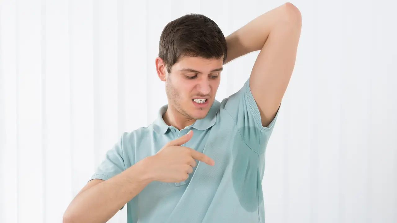 Homem com blusa molhada na axila e cheiro de suor da roupa.