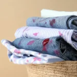 Pilha de roupas dobradas dentro de um cesto de palha.