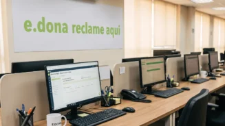 Imagem de uma bancada com computadores e na parede a mensagem da e.dona reclame aqui