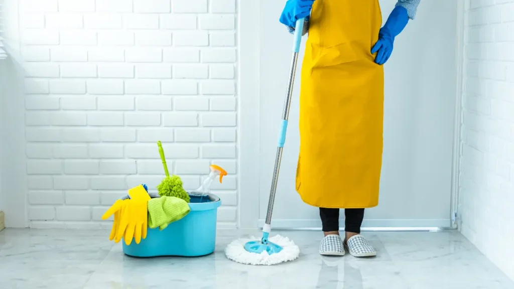 Pessoa com mop e produtos para limpar casa dentro do balde