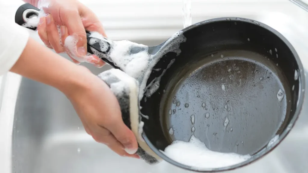 Como limpar panela queimada sem danificar o material pessoa enxaguando uma panela antiaderente