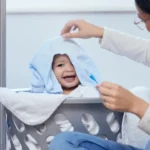 Uma mãe brincando com seu bebe em um cesto de roupas