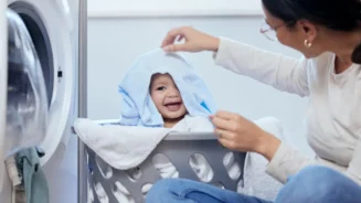 Uma mãe brincando com seu bebe em um cesto de roupas